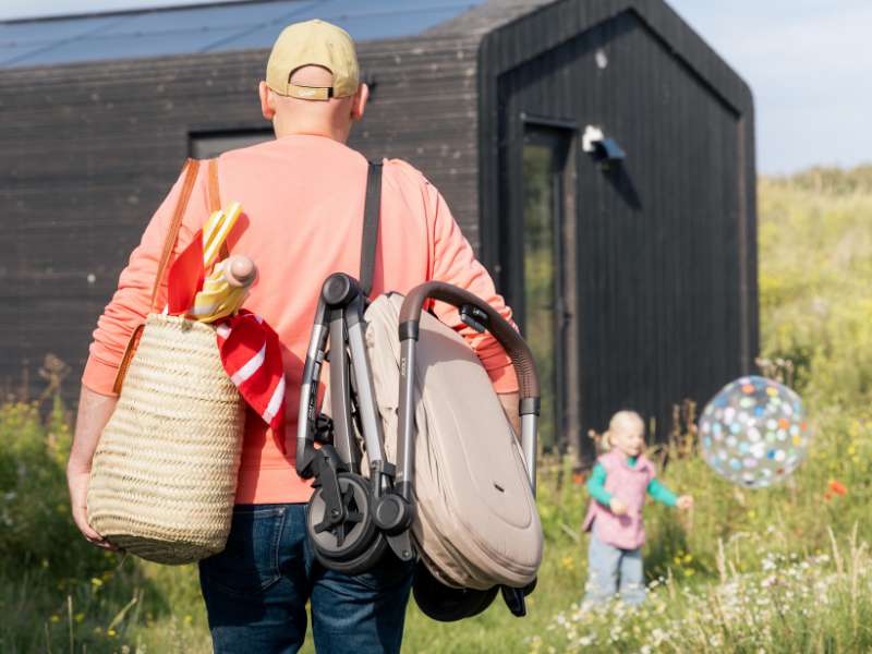 Hombre cargando f&aacute;cilmente la silla de paseo Joolz Aer&sup2; con asiento reversible plegada al hombro gracias a su dise&ntilde;o ultracompacto.